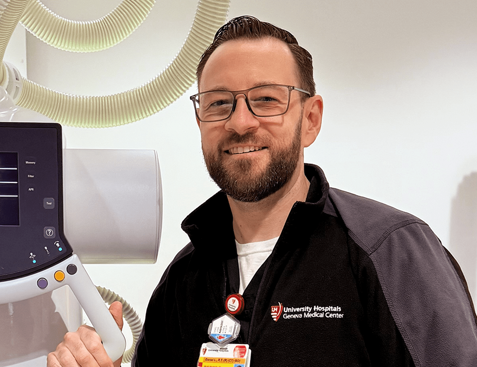 Dan L., lead in radiology, smiling while standing next to an x-ray machine.