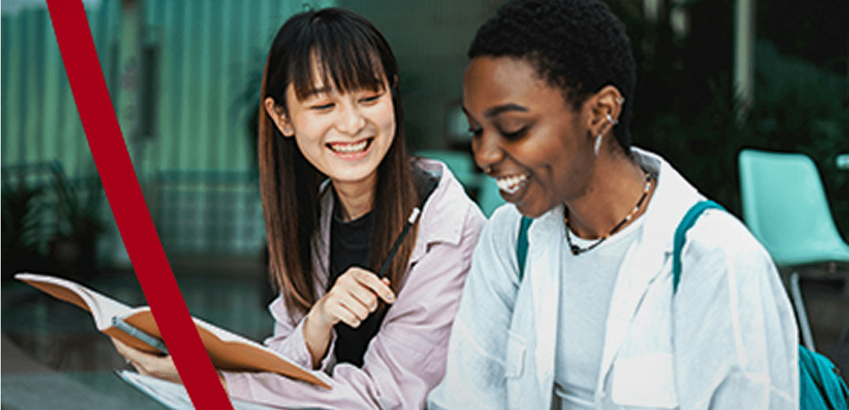 Two smiling young adults study together outdoors.