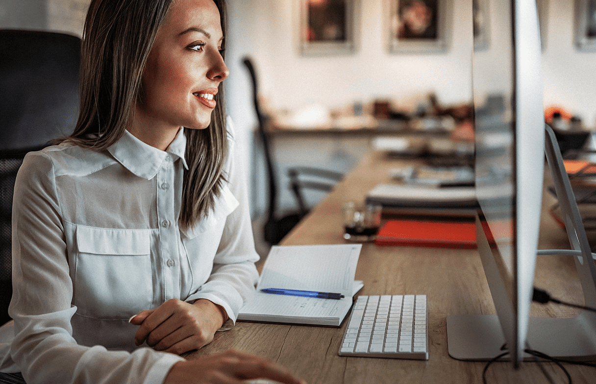 4b3345af1acbf3307f51f7357322841076c23abc A professional woman working at her desk engages in a task on her computer in an office environment.